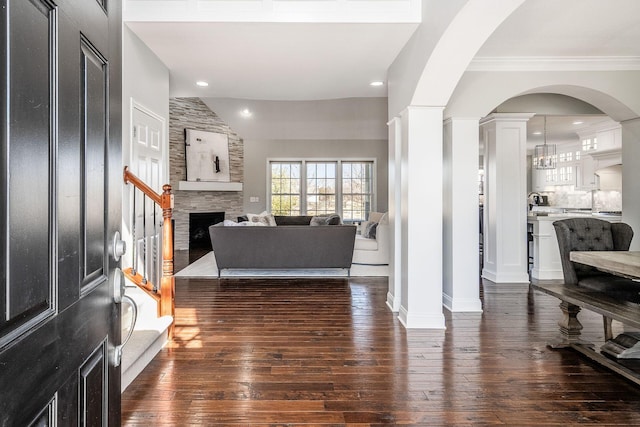 living room with stairway, a fireplace, dark wood-style flooring, vaulted ceiling, and crown molding