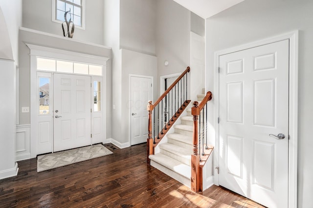 entryway featuring baseboards, stairs, a towering ceiling, and dark wood-style flooring