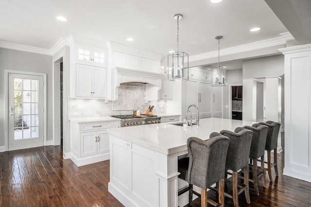 kitchen with a sink, an island with sink, ornamental molding, and light countertops