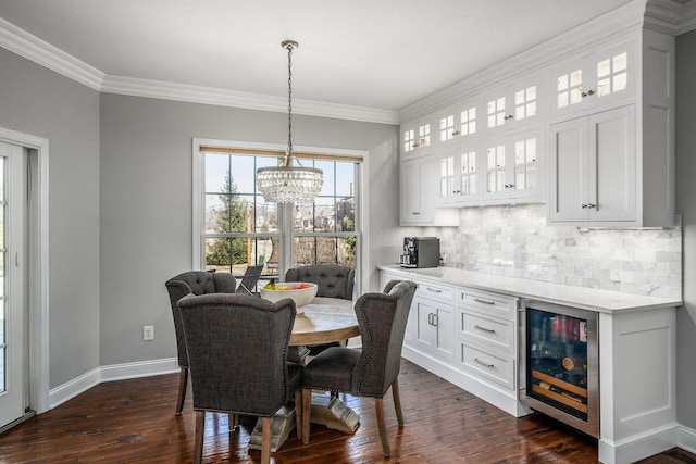 dining room with a notable chandelier, beverage cooler, dark wood finished floors, crown molding, and baseboards