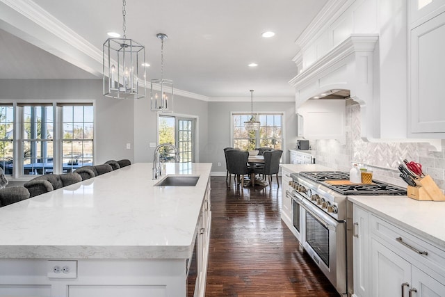 kitchen featuring a center island with sink, ornamental molding, a sink, high end stainless steel range oven, and open floor plan