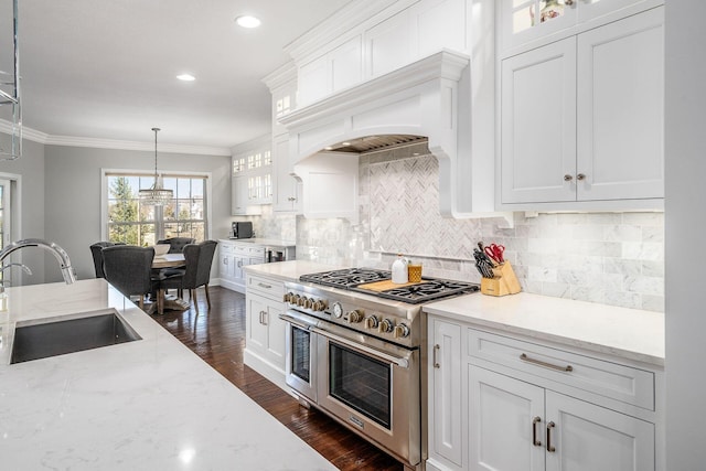 kitchen with a sink, double oven range, crown molding, and white cabinetry