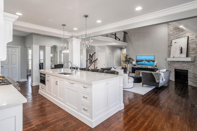 kitchen featuring ornamental molding, a sink, dark wood finished floors, open floor plan, and a fireplace