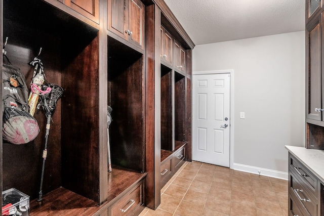 mudroom featuring light tile patterned floors, baseboards, and a textured ceiling