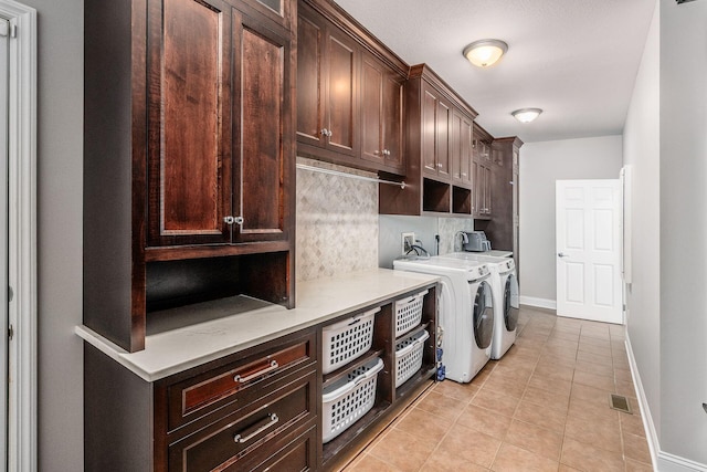 laundry area featuring visible vents, baseboards, light tile patterned flooring, cabinet space, and independent washer and dryer