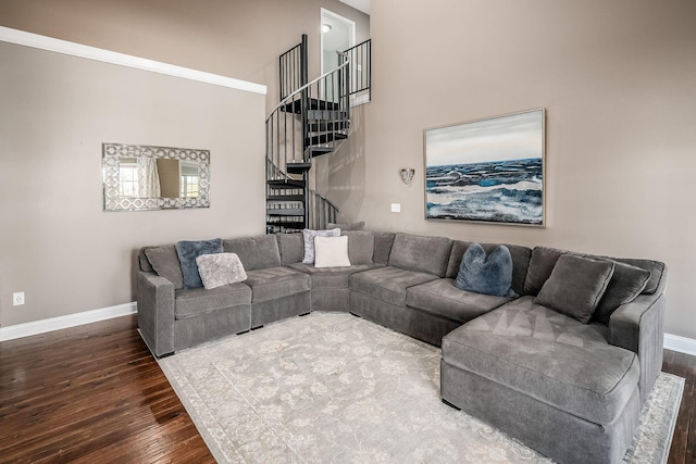 living area featuring a towering ceiling, stairs, baseboards, and wood finished floors