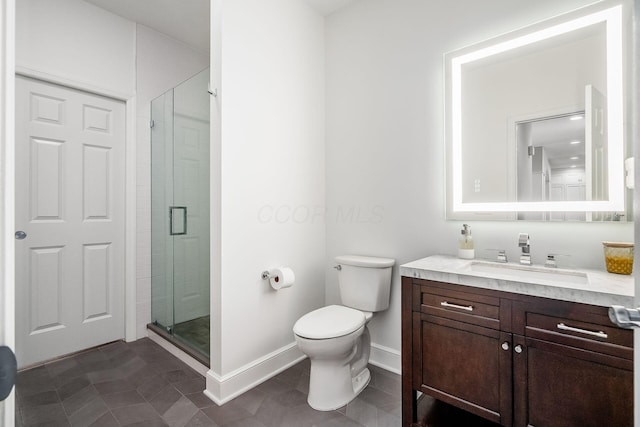 bathroom with a stall shower, toilet, vanity, and baseboards