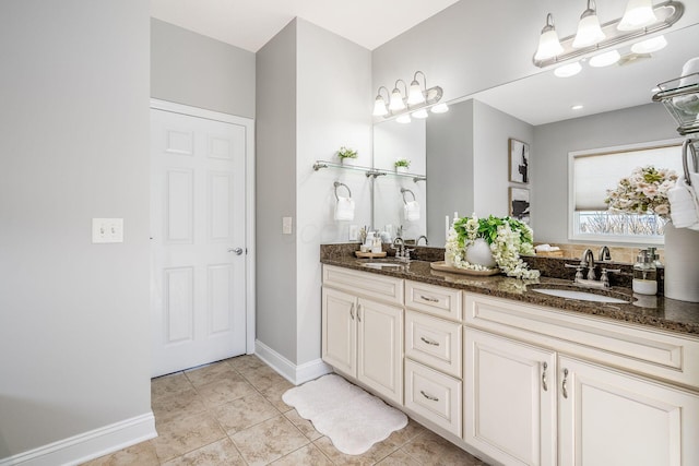 bathroom with a sink, baseboards, double vanity, and tile patterned floors