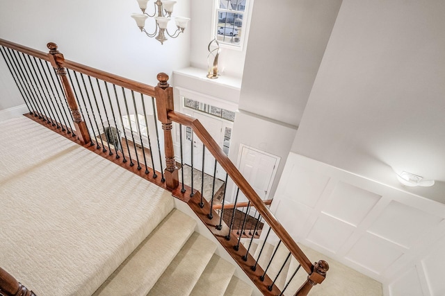 stairs featuring a decorative wall, carpet, and a chandelier