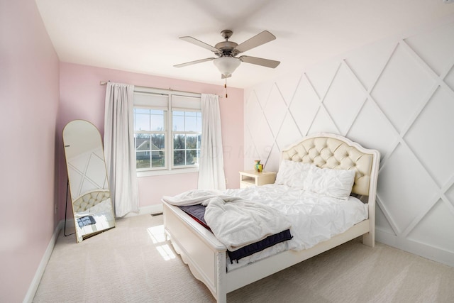 carpeted bedroom with an accent wall, a ceiling fan, and baseboards