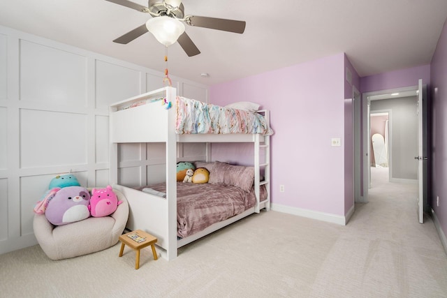 bedroom featuring a decorative wall, baseboards, carpet, and a ceiling fan