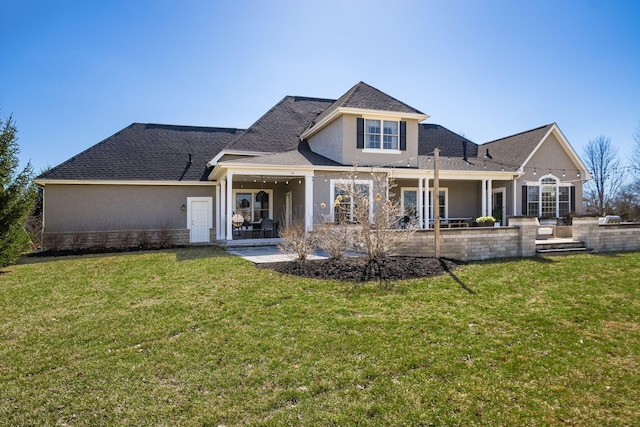 rear view of property featuring a lawn, roof with shingles, a patio, and stucco siding