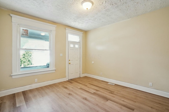 foyer entrance featuring light wood-style flooring, a healthy amount of sunlight, and a textured ceiling