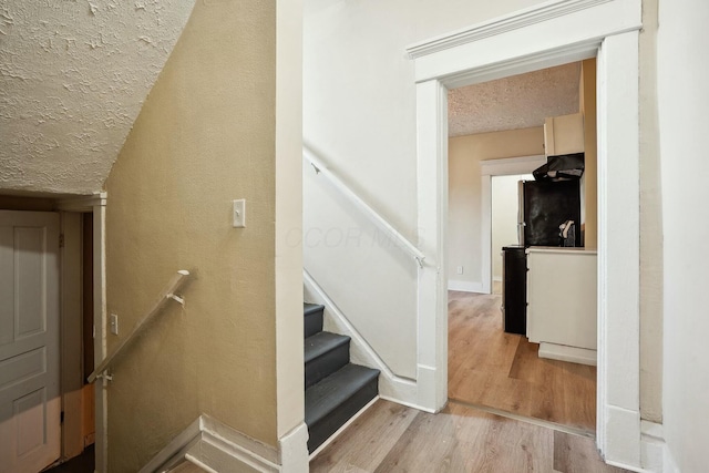 staircase with baseboards, a textured ceiling, and wood finished floors