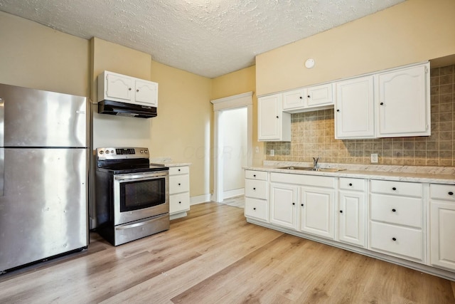 kitchen with under cabinet range hood, light wood-style flooring, stainless steel appliances, white cabinetry, and a sink