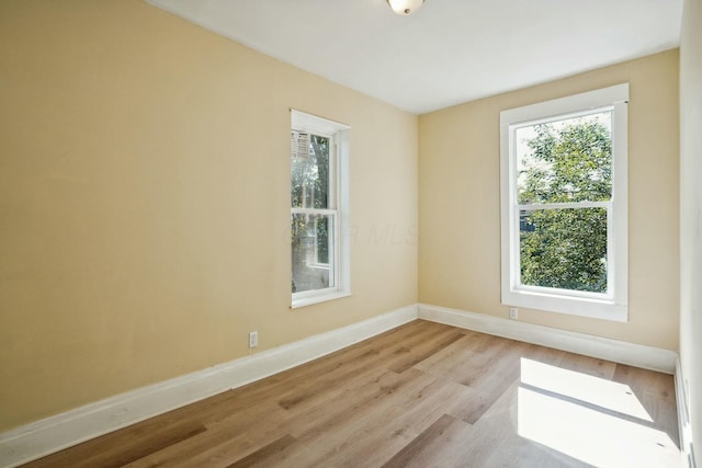 spare room featuring baseboards and light wood finished floors