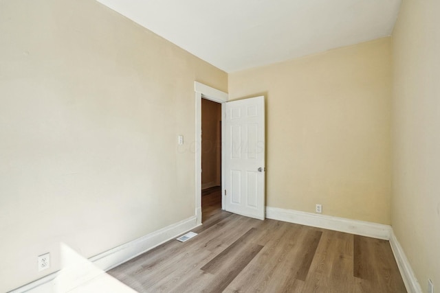 spare room with wood finished floors, visible vents, and baseboards