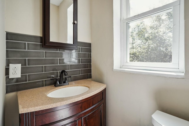 half bathroom featuring tasteful backsplash, vanity, and toilet