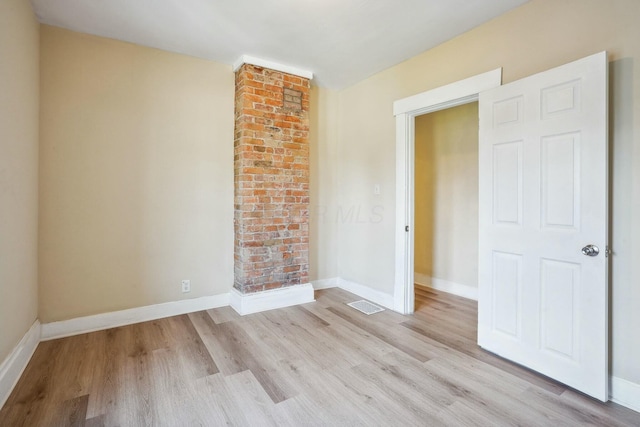 spare room featuring visible vents, light wood-style floors, and baseboards