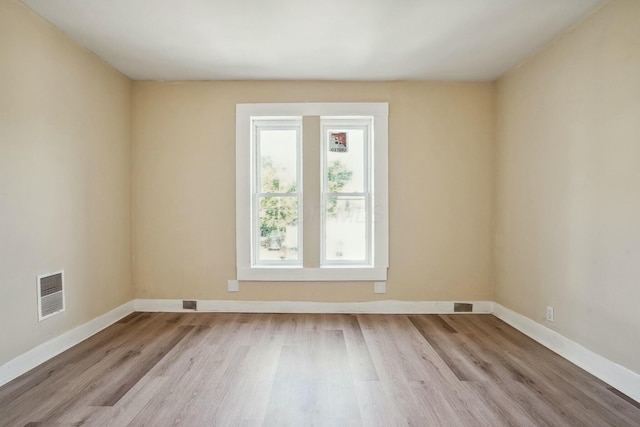 spare room with visible vents, baseboards, and wood finished floors