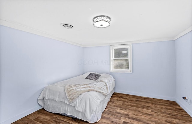 bedroom with wood finished floors, visible vents, and baseboards