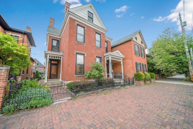 view of front of home featuring brick siding, a chimney, and a fenced front yard