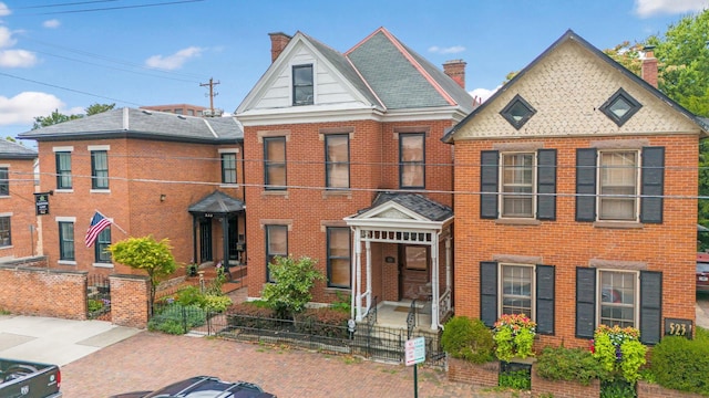 view of front facade with a fenced front yard, brick siding, and a chimney