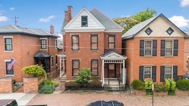 view of front facade with brick siding, a chimney, a fenced front yard, and a gate