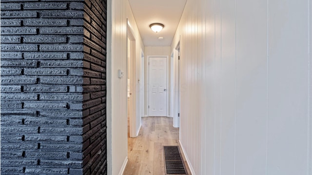 corridor featuring wood finished floors, visible vents, and baseboards