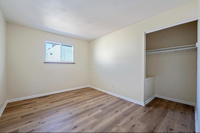 unfurnished bedroom with wood finished floors, a closet, and baseboards