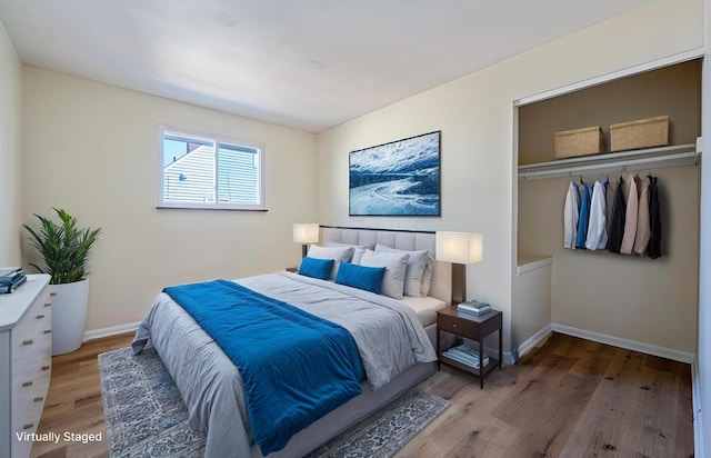 bedroom with wood finished floors, baseboards, and a closet