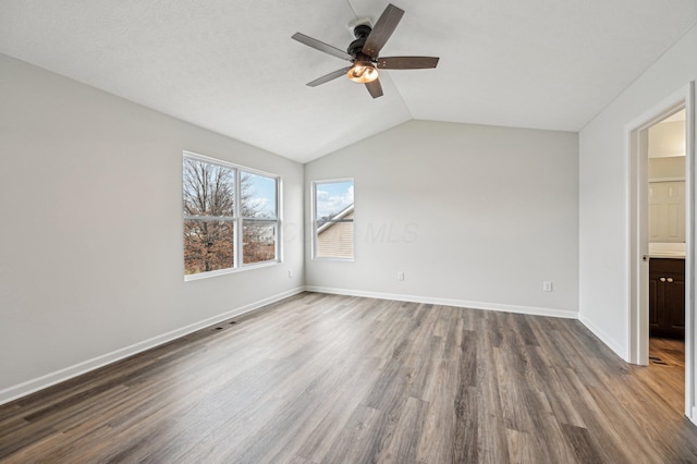 unfurnished bedroom with ceiling fan, dark wood-type flooring, baseboards, and vaulted ceiling