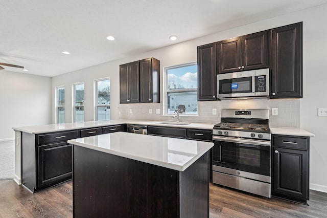 kitchen with a sink, a peninsula, dark wood finished floors, and stainless steel appliances