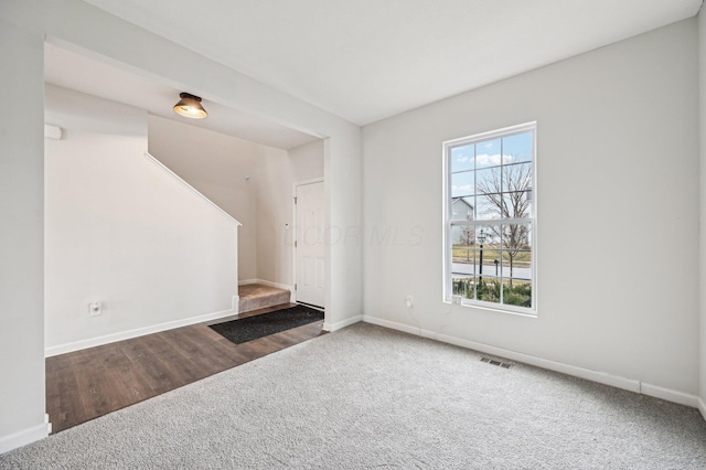 unfurnished living room featuring visible vents, carpet floors, and baseboards