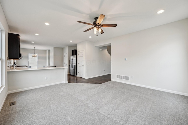 unfurnished living room with recessed lighting, visible vents, dark carpet, and baseboards