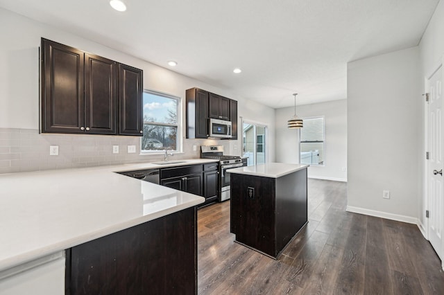 kitchen featuring dark wood finished floors, a sink, tasteful backsplash, and stainless steel appliances