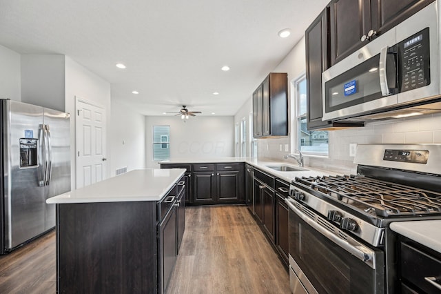 kitchen with backsplash, appliances with stainless steel finishes, wood finished floors, and a sink