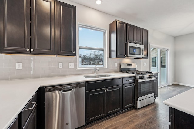 kitchen with backsplash, dark wood-type flooring, light countertops, appliances with stainless steel finishes, and a sink