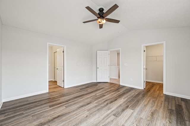 unfurnished bedroom featuring a walk in closet, lofted ceiling, wood finished floors, and a closet