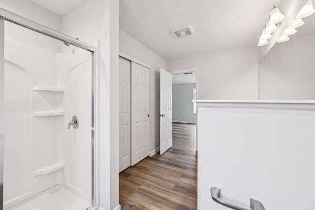 bathroom featuring visible vents, a shower stall, and wood finished floors