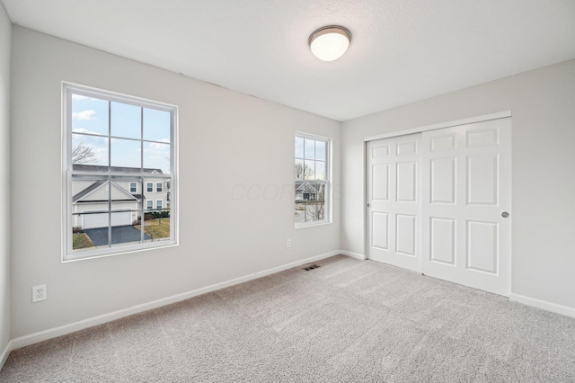 unfurnished bedroom with carpet flooring, baseboards, visible vents, and a closet