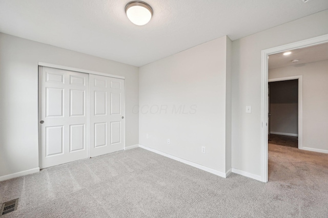 unfurnished bedroom with visible vents, baseboards, a closet, and carpet flooring