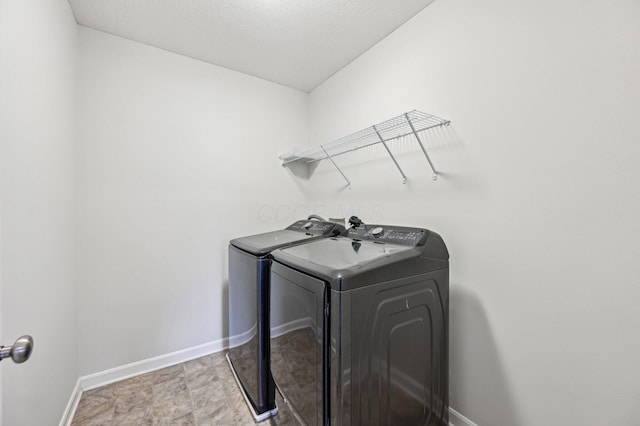 washroom featuring baseboards, washing machine and dryer, and laundry area