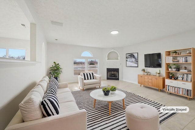 living area with light tile patterned floors, visible vents, baseboards, and a fireplace