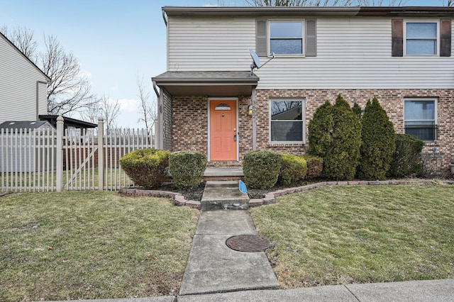 view of front facade with a front yard, fence, and brick siding