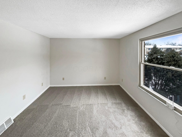 carpeted empty room with baseboards, visible vents, and a textured ceiling