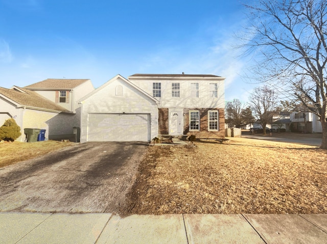 traditional-style home featuring aphalt driveway, an attached garage, and brick siding