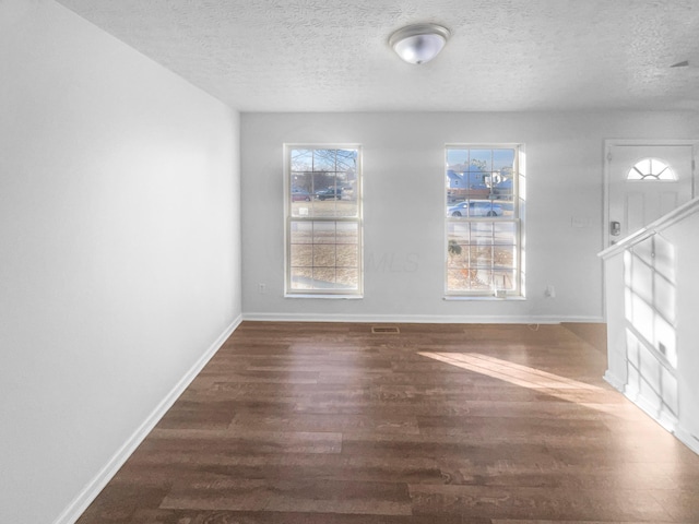 interior space featuring visible vents, wood finished floors, baseboards, and a textured ceiling