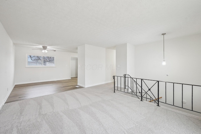 empty room with a textured ceiling, carpet flooring, baseboards, and ceiling fan