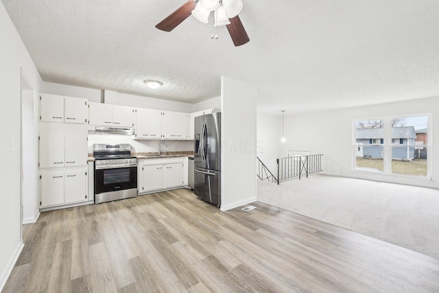 kitchen featuring a sink, under cabinet range hood, a textured ceiling, white cabinetry, and appliances with stainless steel finishes